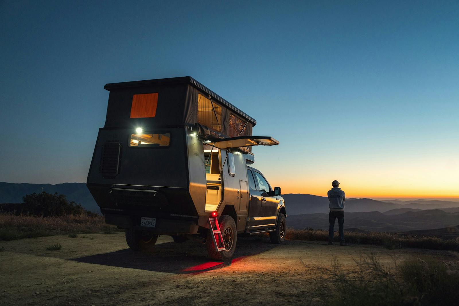 A camper van at dusk with a man enjoying the scenic desert landscape.